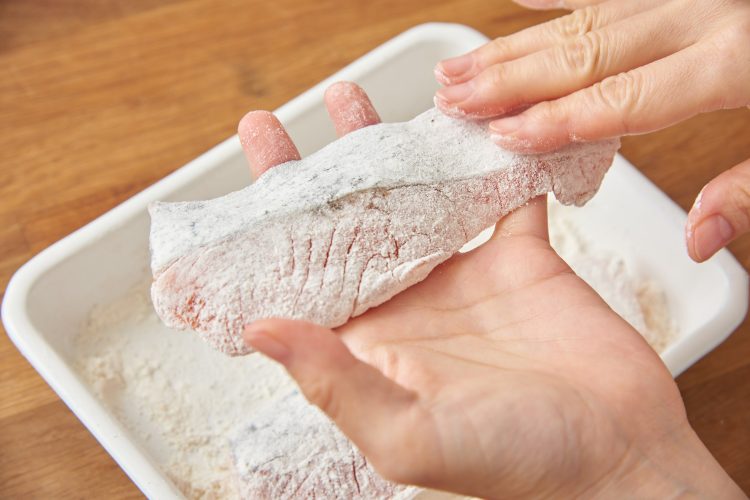 小麦粉をまぶした生鮭を軽く叩いて余分な粉をはたく