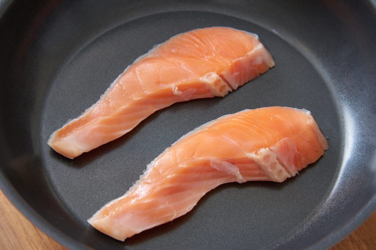 加熱前のフライパンに、皮面を下にして塩鮭を並べる