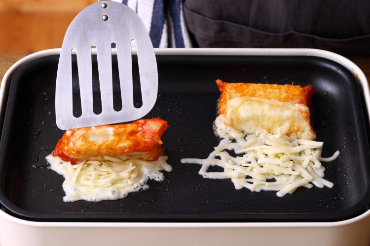 焼き色がついたチーズで餅を巻いているイメージ