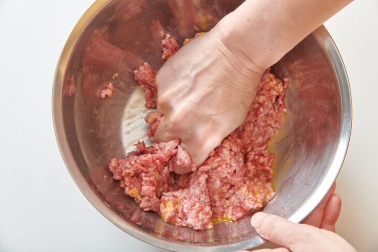 ハンバーグのタネを手でつかむようにして混ぜ合わせる