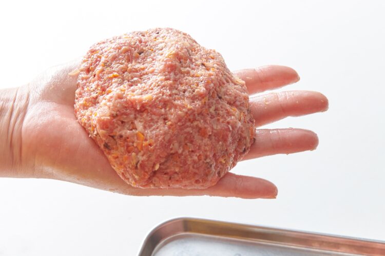 ハンバーグのタネを片手からもう一方の手に落とす