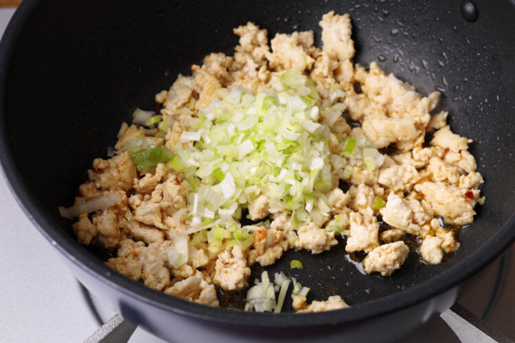 挽き肉に豆板醤と長ねぎを加えて炒めている様子