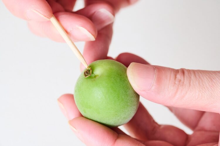 竹串または爪楊枝で青梅のヘタを取り除く