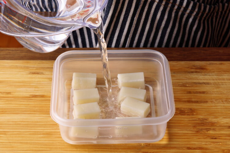 2.耐熱容器やタッパーに水にくぐらせた餅を間隔をあけて並べ、餅に水（分量外）を表面が被るまで注ぐ。