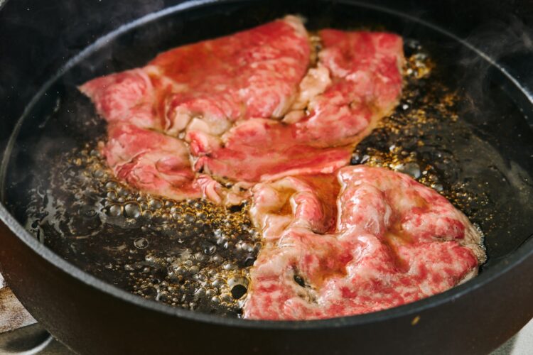 片面に焼き目がつくまで牛肉を焼く様子