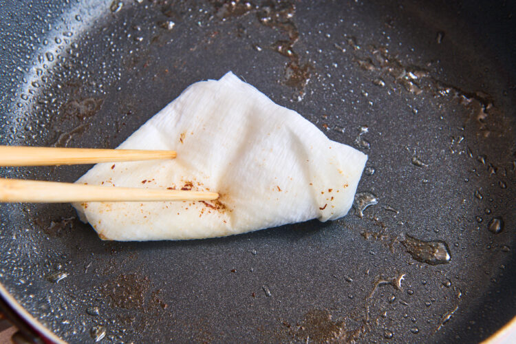 フライパンの余分な脂をふき取る