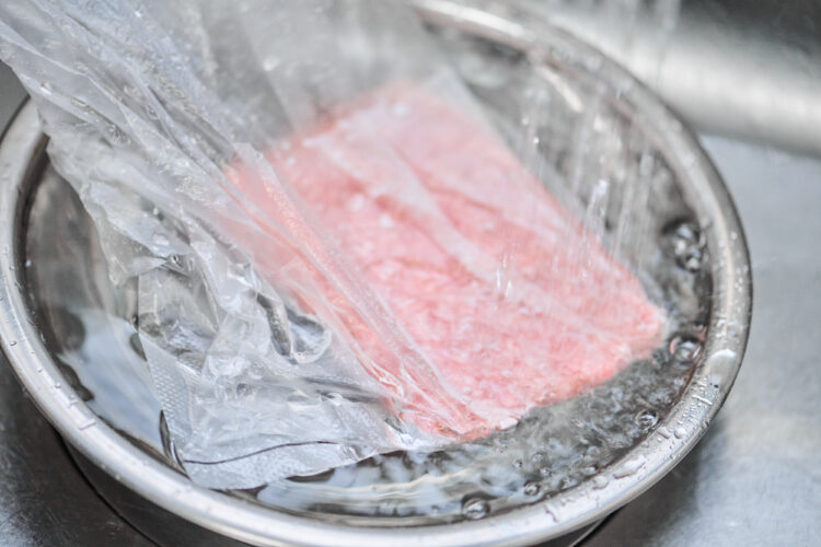ビニール袋の中に冷凍肉を入れ、水を張ったボウルの中に浸ける