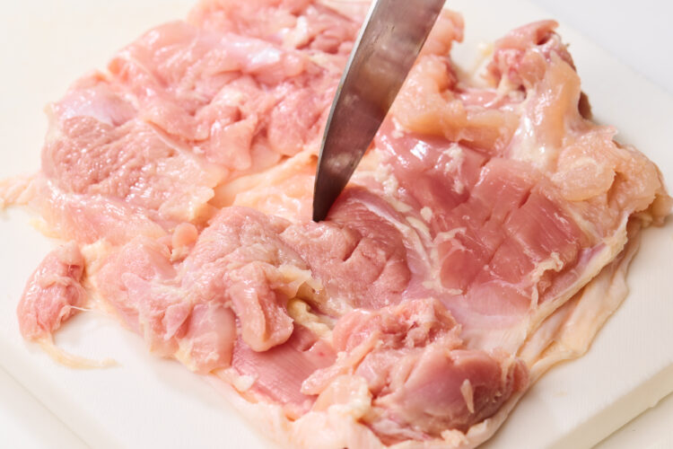 鶏肉に刃先を叩き込む写真