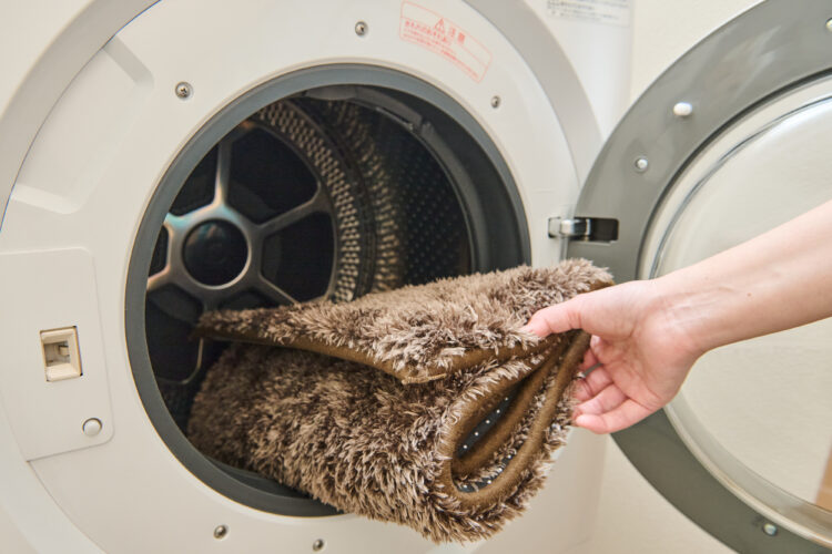 カーペット・ラグをくるくると丸め、洗濯機に入れる