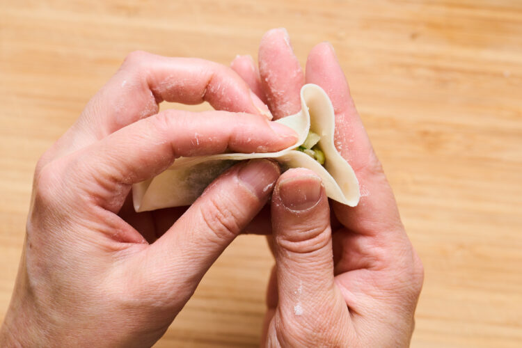 4.片側の端を、人差し指で奥に倒しながら押してひだを作る